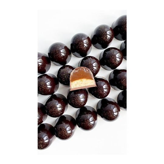 Uppskuren mörk chokladpralin med krämig fyllning och gyllene glitter