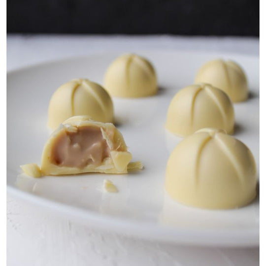 Vit chokladpralin med krämig fyllning uppbiten