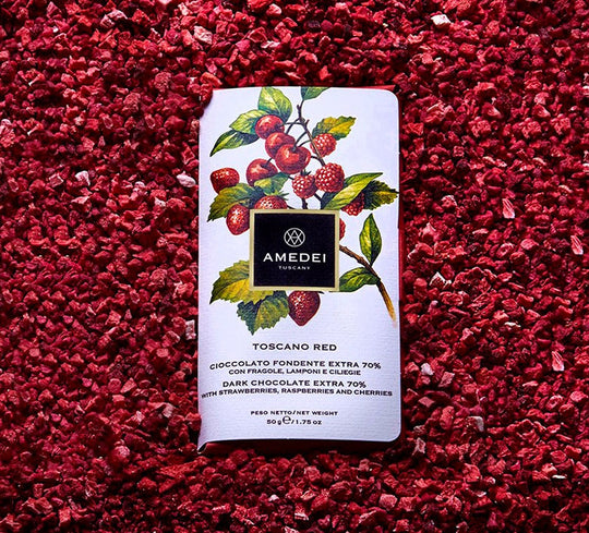 Chokladshopen Amedei Toscano Red mörk choklad 70% med frystorkade jordgubbar, hallon och körsbär på en bädd av bär.