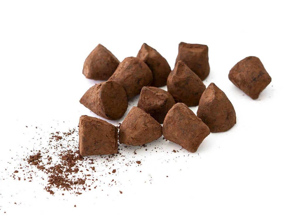Chokladshopen La Praline hasselnötstryfflar pudrade med kakao på vit bakgrund