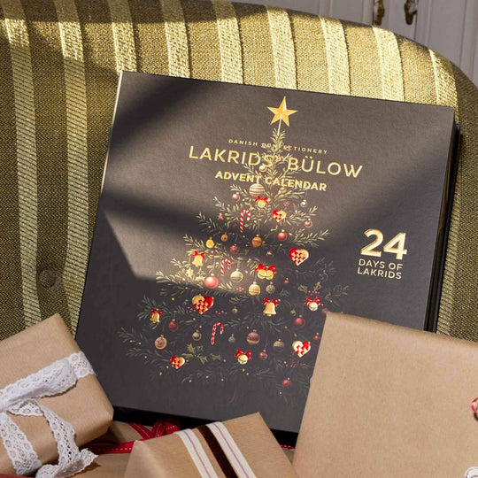 Chokladshopen Lakrids By Bülow adventskalender med svart och guldig julgransillustration och 24 luckor för gourmetlakrits