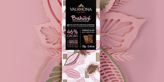Chokladshopen Valrhona Bahibe 46% mjölkchokladkaka på 70g med elegant förpackning mot en stiliserad blommig bakgrund.