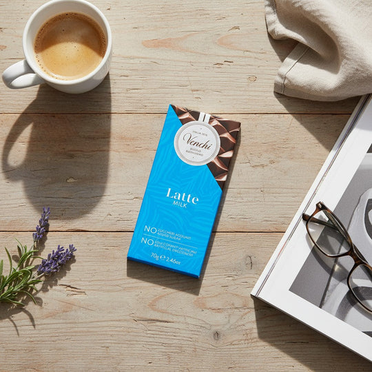 Chokladshopen Venchi mjölkchoklad utan tillsatt socker på ett rustikt träbord med kaffe, tidning och lavendel.