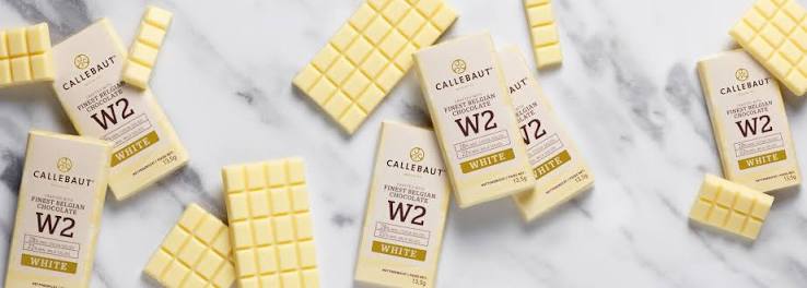 Unwrapped Callebaut white chocolate bars on marble surface