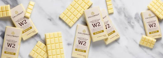 Unwrapped Callebaut white chocolate bars on marble surface